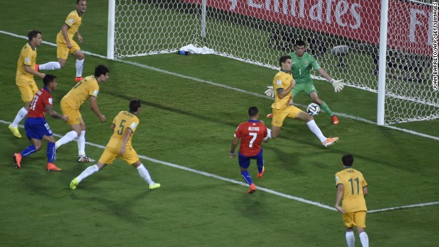 Chile forward Alexis Sanchez kicks the ball past two Australians to score the opening goal of the match.