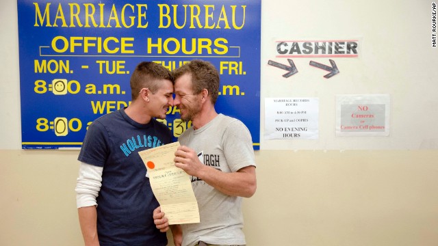 William Roletter, left, and Paul Rowe, right, press close to each other after having their photo taken with their newly acquired marriage certificate Wednesday, May 21, at City Hall in Philadelphia.