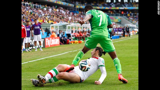 Iran's Andranik Teymourian slides under Nigeria's Ahmed Musa to take the ball away.