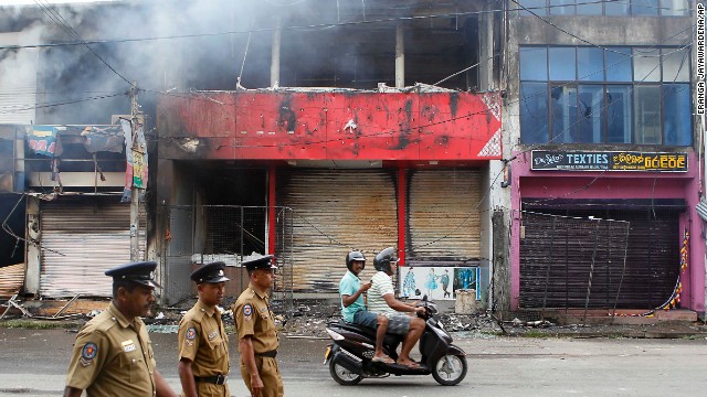 Police officers on a street in Aluthgama as shops burn. A curfew was put in place to prevent further violence.