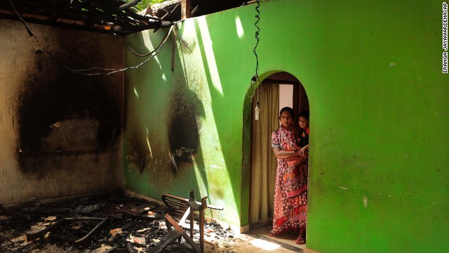 A Muslim mother and child take in damage to their house.