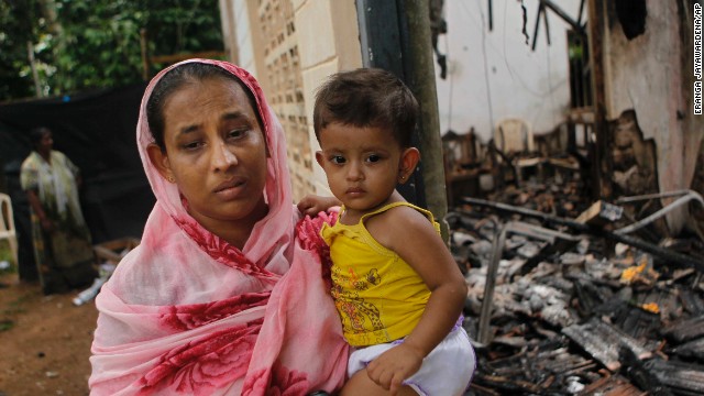 A Sri Lankan Muslim woman carries her daughter outside her burnt house after at least three Muslims were killed and 80 injured in clashes with Buddhists last month. The sectarian riots in and around the town of Aluthgama, in southern Sri Lanka, followed demonstrations by the hardline Buddhist group Bodu Bala Sena, police said. Homes and shops were looted and burned.