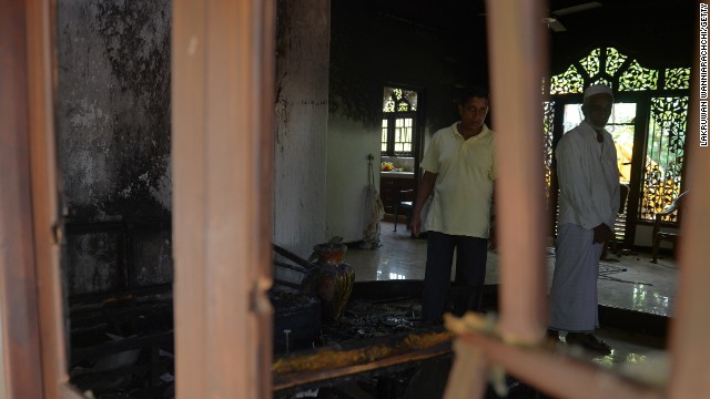 Sri Lankan residents survey the damage to a damaged Muslim-owned home.
