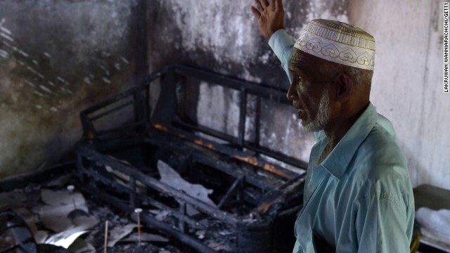 A Sri Lankan resident surveys the damage to a charred Muslim-owned home.