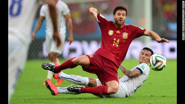 Spanish midfielder Xabi Alonso, left, falls to the ground near Chilean midfielder Charles Aranguiz.