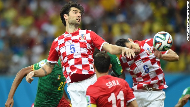 Croatian defender Vedran Corluka, center, heads the ball.