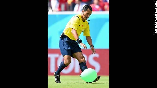 Referee Enrique Osses tries to catch a balloon that came onto the field.