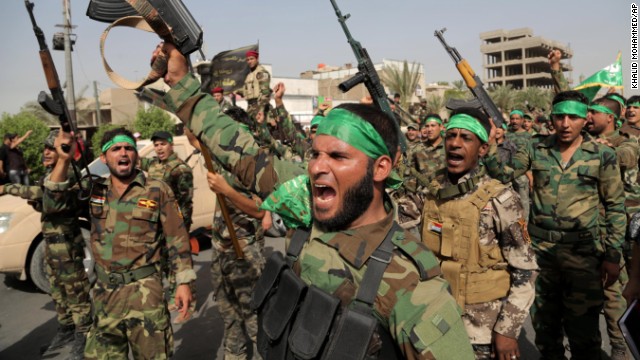 "Peace Brigade" volunteers raise their weapons and chant slogans during a parade in the Shiite stronghold of Sadr City on Saturday, June 21, in Baghdad. The armed group was formed to protect Shiite holy shrines against possible attacks by Sunni militants.