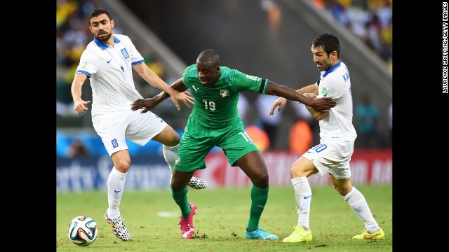 Yaya Toure of the Ivory Coast is challenged by Giannis Maniatis, left, and Giorgos Karagounis of Greece.