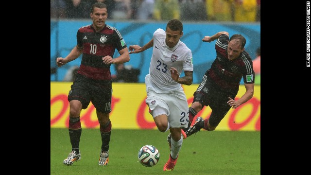 Lukas Podolski and Benedikt Hoewedes of Germany chase after Fabian Johnson of the United States.