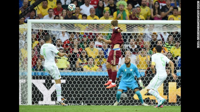 Russia forward Alexander Kokorin, center, scores his team's first goal past Algeria's goalkeeper Rais Mbohli, in blue.