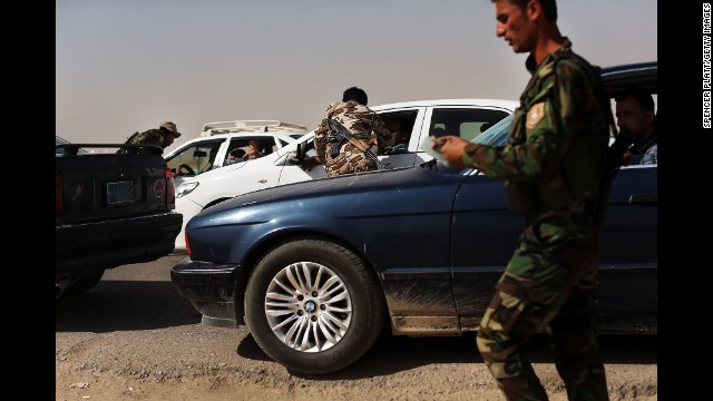 Peshmerga fighters, or Kurdish warriors, check cars at the entrance to a temporary displacement camp in Khazair, Iraq, for people caught in the fighting in and around the city of Mosul on Thursday, June 26. 