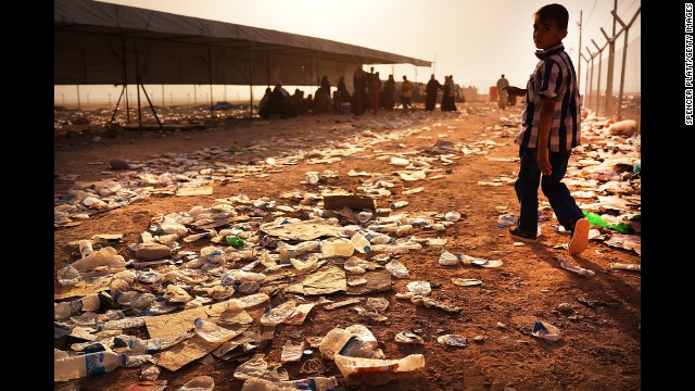 A child walks over discarded water bottles and trash at a registration area in the displacement camp in Khazair on June 26.