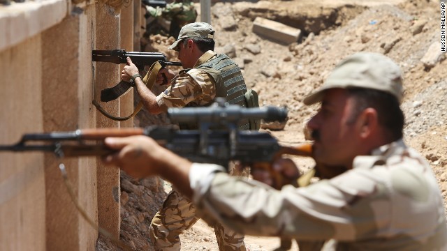 Kurdish Peshmerga take their positions behind a wall on the front line of the conflict with ISIS militants in Tuz Khormato, Iraq, on Wednesday, June 25.