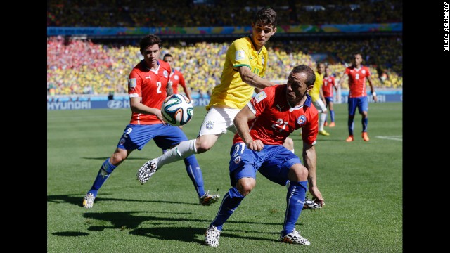 Brazil's Oscar, center, is challenged by Chile's Marcelo Diaz, right, on June 26.