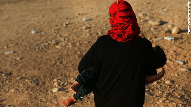 An Iraqi woman walks with her child outside of a displacement camp on June 28 in Khazair, now home to an estimated 1,500 internally displaced persons.