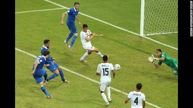 Sokratis Papastathopoulos of Greece, left, shoots and scores late in the second half to tie Costa Rica during a game in Recife, Brazil, on Sunday, June 29. The elimination-round game ended with a final score of 1-1. Costa Rica advanced by winning a penalty kick shootout.