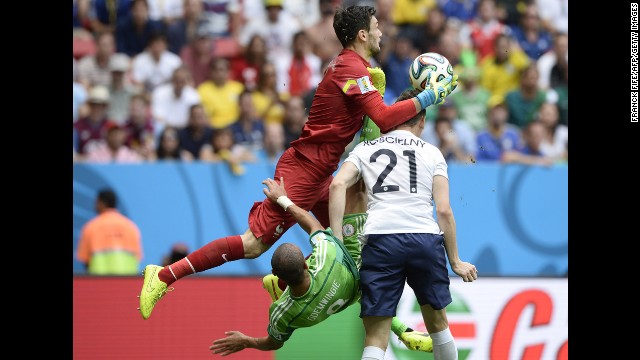 French goalkeeper Hugo Lloris collects the ball as Odemwingie attempts to score during the first half.