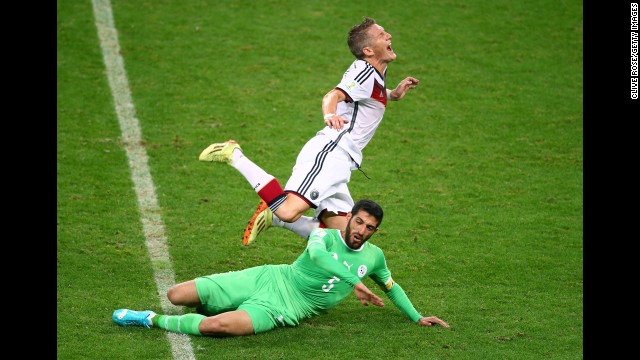 Algerian defender Rafik Halliche slides under Germany's Bastian Schweinsteiger. Halliche received a yellow card for the challenge.