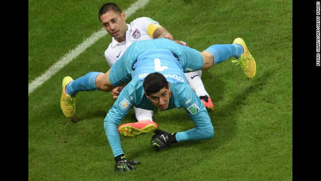 Belgium's goalkeeper, Thibaut Courtois, falls on U.S. forward Clint Dempsey.