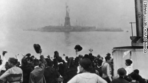 Immigrants traveling aboard a ship celebrate as they catch their first glimpse of the Statue of Liberty and Ellis Island in New York Harbor in 1915. 