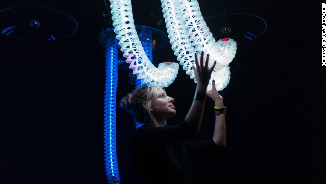A girl plays with responsive snake-like robotic arms in interactive sculpture "Petting Zoo" by Minimaforms.