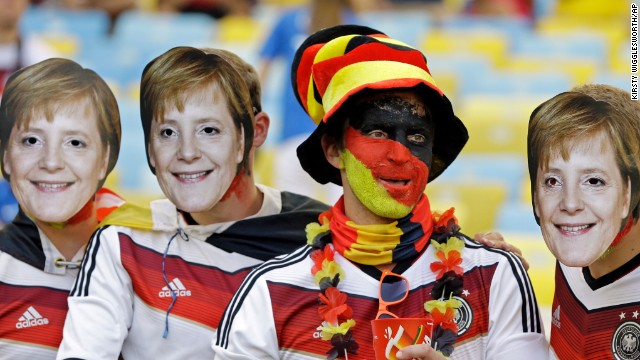 A Germany fan poses with friends wearing masks of German Chancellor Angela Merkel.