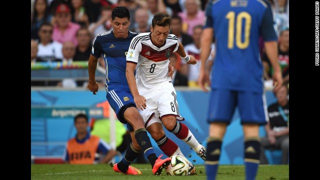 German midfielder Mesut Ozil, center, tries to dribble past Argentine midfielder Enzo Perez in the first half.