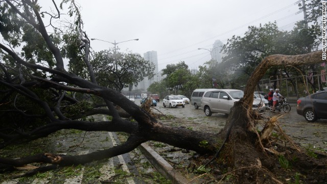 Motorists pick their way past fallen trees along a highway as Typhoon Rammasun exacts a toll on Manila.