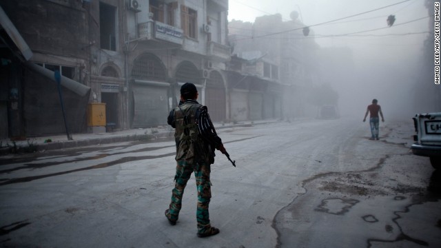 A rebel fighter stands on a dust-covered street in Aleppo on Monday, July 21.