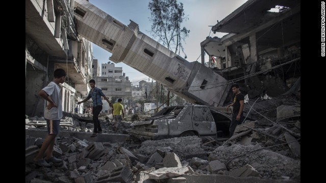 Palestinians walk under the collapsed minaret of a destroyed mosque in Gaza City on July 30.