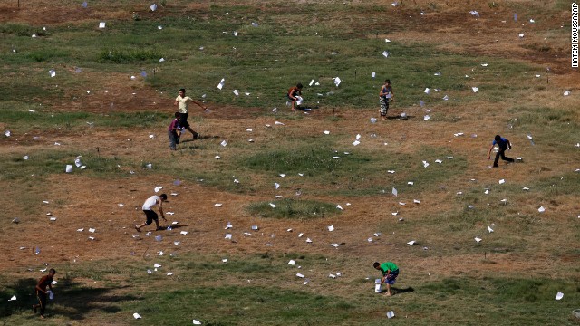 Palestinians gather leaflets that fell from an Israeli plane on July 30. The leaflets warned residents of airstrikes in Gaza City.