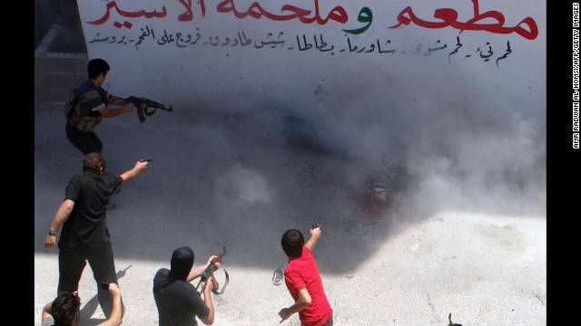 Rebel fighters execute two men Friday, July 25, in Binnish, Syria. The men reportedly were charged by an Islamic religious court with detonating several car bombs. 