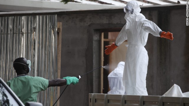 Nurses wearing protective clothing are sprayed with disinfectant Friday, August 1, in Monrovia after they prepared the bodies of Ebola victims for burial.