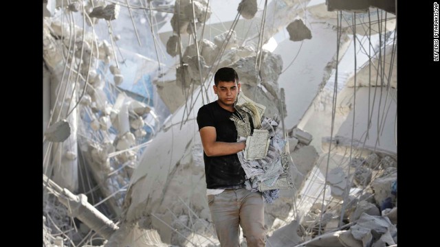 A young Palestinian carries damaged copies of the Quran from the rubble of the Imam Al Shafaey mosque in Gaza City on August 2.