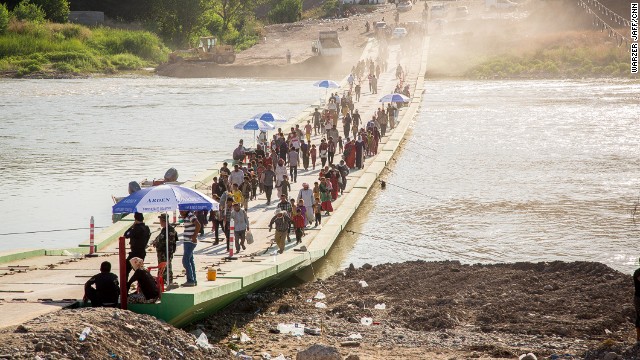 Thousands trudge across a river to seek humanitarian aid in Syria.