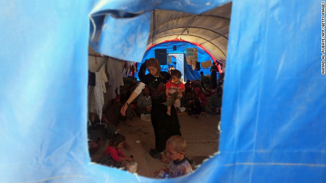 A Yazidi woman and children take shelter inside a tent at the Bajid Kandala camp on August 13.