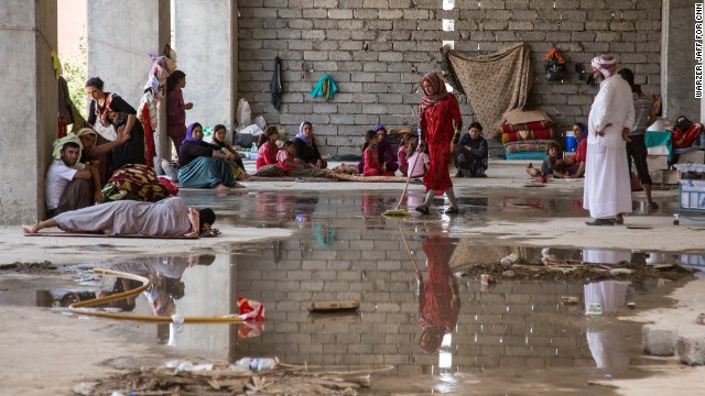 A Yazidi family from Sinjar cleans a spot for themselves in a derelict building that houses more than a thousand other refugees on Thursday, August 14, in Zakho, Iraq. 