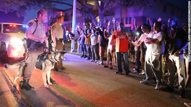 Police officers and protesters confront each other on Saturday, August 9, the same day Michael Brown was shot and killed.