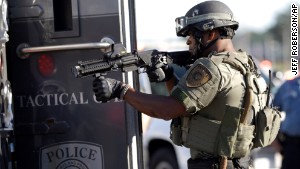 A member of the St. Louis County Police Department points his weapon in the direction of a group of protesters in Ferguson on Wednesday.