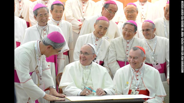 Pope Francis laughs with bishops as he signs a guestbook Thursday, August 14, at the headquarters of the Korean Episcopal Conference in Seoul, South Korea.