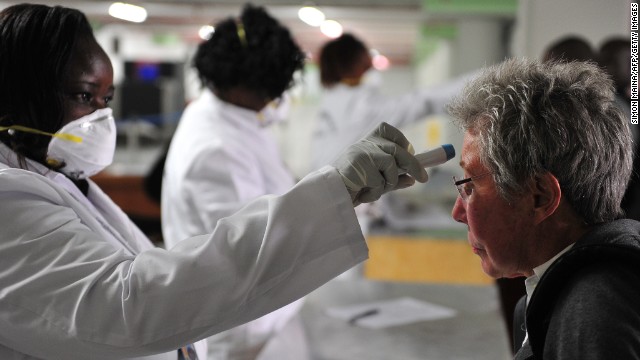 Kenyan health officials take passengers' temperature as they arrive at the Jomo Kenyatta International Airport on Thursday, August 14, in Nairobi, Kenya.