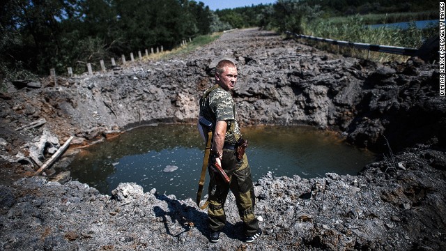 A pro-Russian gunman stands next a bomb crater after shelling near Donetsk on Thursday.