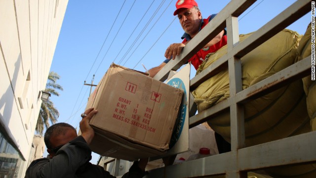 Volunteers of the Iraqi Red Crescent Society unload boxes of goods before distributing them August 14 to families who fled from ISIS.