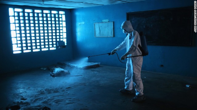 A health worker disinfects a corpse after a man died in a classroom being used as an Ebola isolation ward Friday, August 15, in Monrovia.