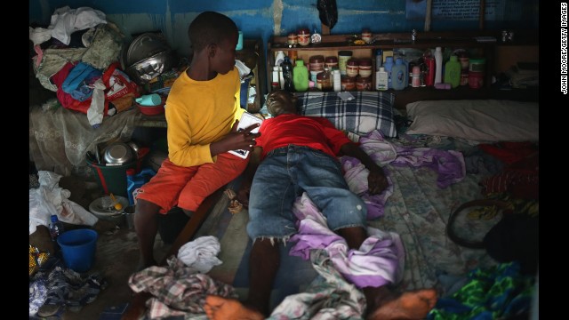 A boy tries to prepare his father before they are taken to an Ebola isolation ward August 15 in Monrovia.