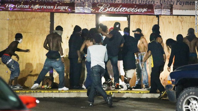 People loot the Ferguson Market and Liquor store on August 16. Several businesses were looted as police held their positions nearby.