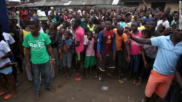 A crowd enters the grounds of an Ebola isolation center in the West Point slum on August 16. The mob was reportedly shouting, 