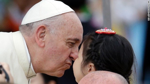 Pope Francis kisses a child on August 17 upon arrival for the mass.