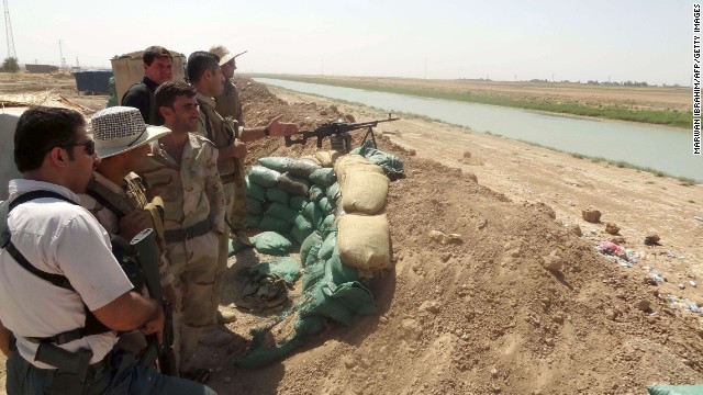 Kurdish Peshmerga fighters stand behind a sand barricade set up close to the village of Bashir, Iraq, on August 17. 